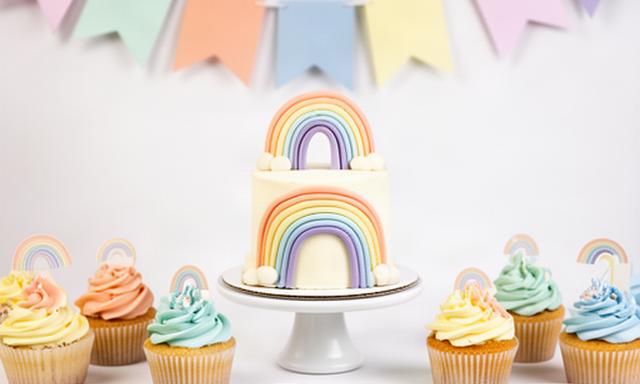 Mini mesa dulce con smash cake, cupcakes y banderín de arcoíris para un primer cumpleaños